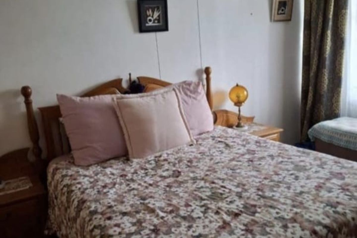 A bedroom featuring tiled flooring and a window with curtains, providing a functional and comfortable living space.