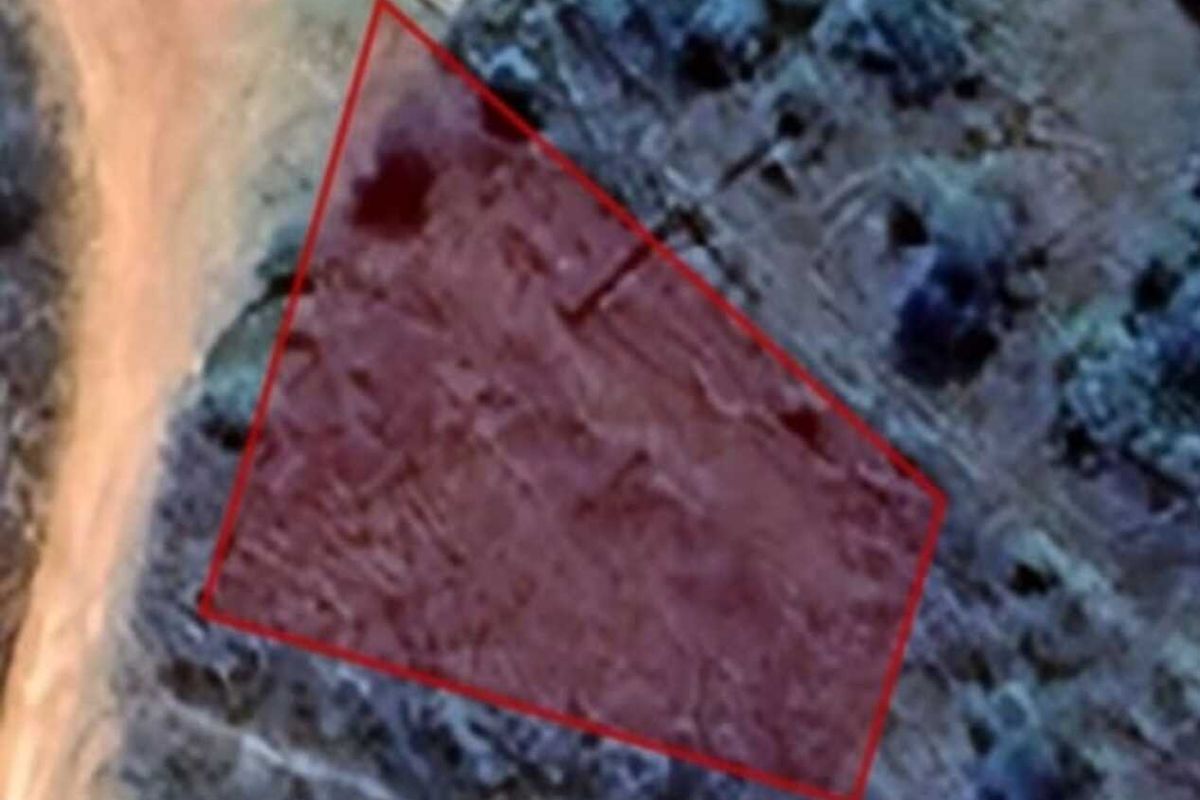 Aerial view of a vacant residential plot with a red boundary overlay indicating the property perimeter.