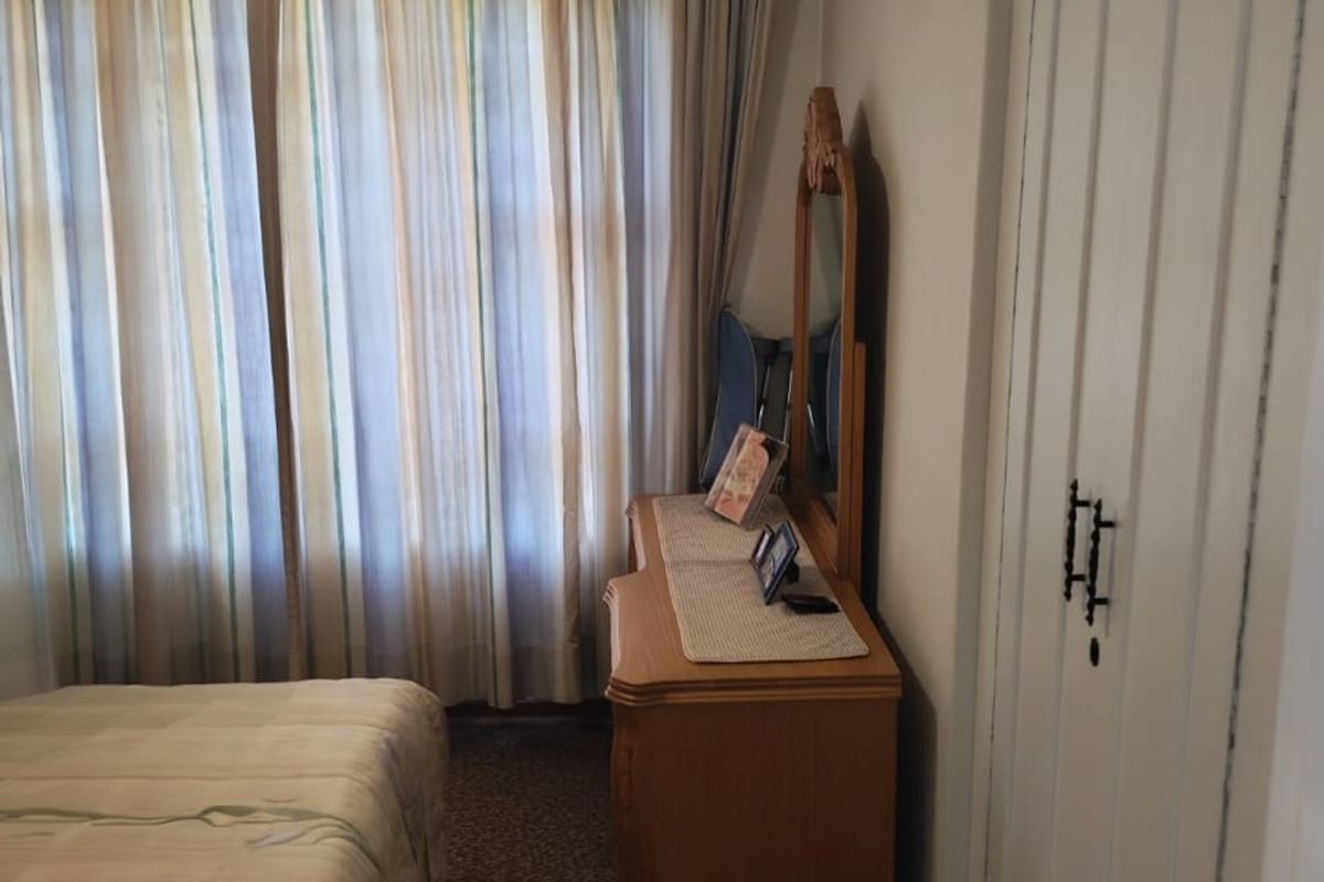 A bedroom featuring built-in cupboards, carpeted flooring, and a ceiling fan, offering a functional and comfortable living space.