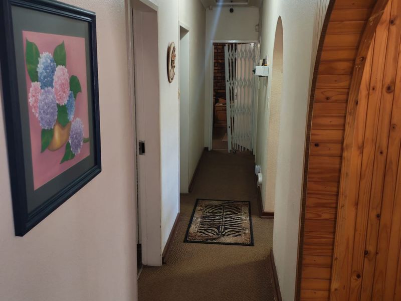 A functional interior hallway featuring a distinctive wooden arched doorway and carpeted flooring, providing access to multiple rooms within the home.