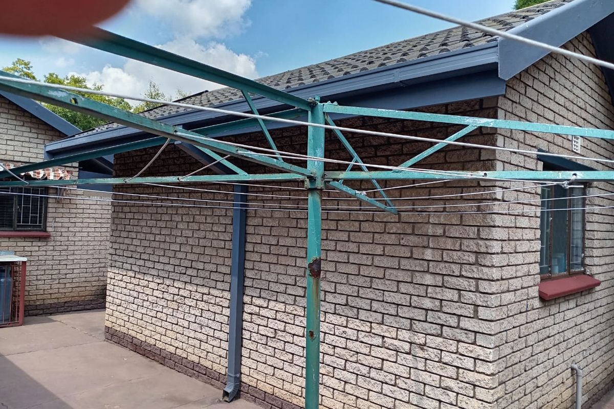 Exterior view of the rear brick building featuring a metal rotary washing line and paved outdoor area.