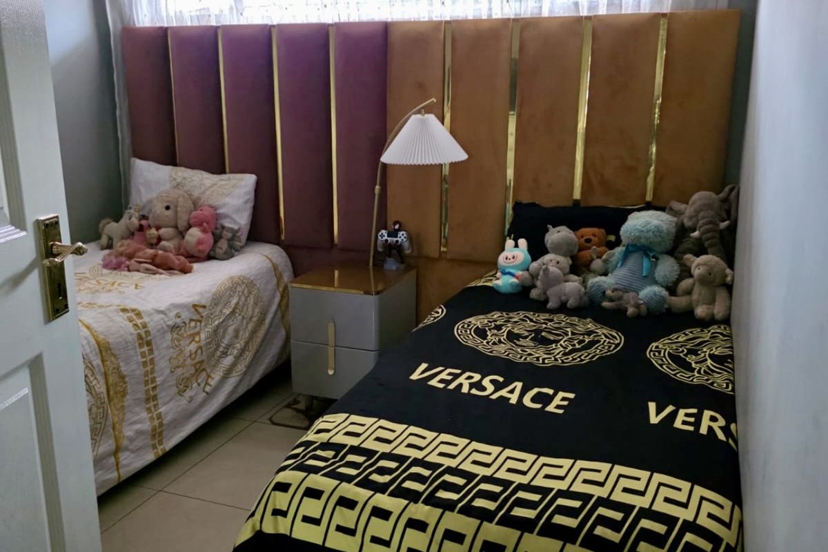 A compact bedroom featuring tiled flooring, a ceiling fan, and a custom built-in headboard spanning the width of the wall.