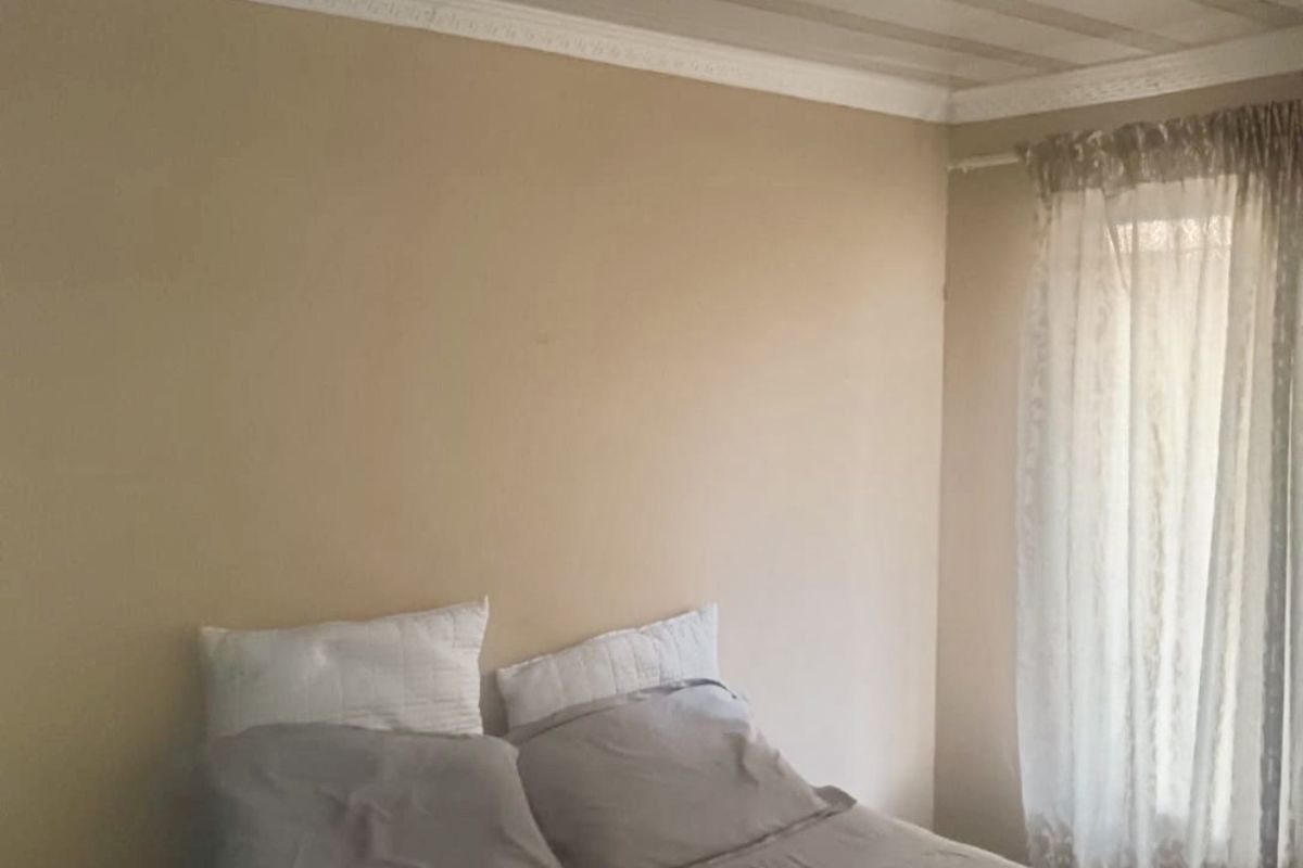 A bedroom featuring a neutral wall color, decorative crown molding, and a textured ceiling finish with a central light fixture.