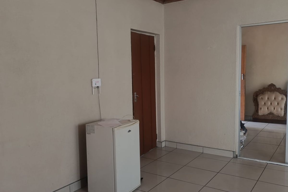 A simple interior space featuring tiled flooring, a timber-clad ceiling, and a doorway leading to an adjacent room.