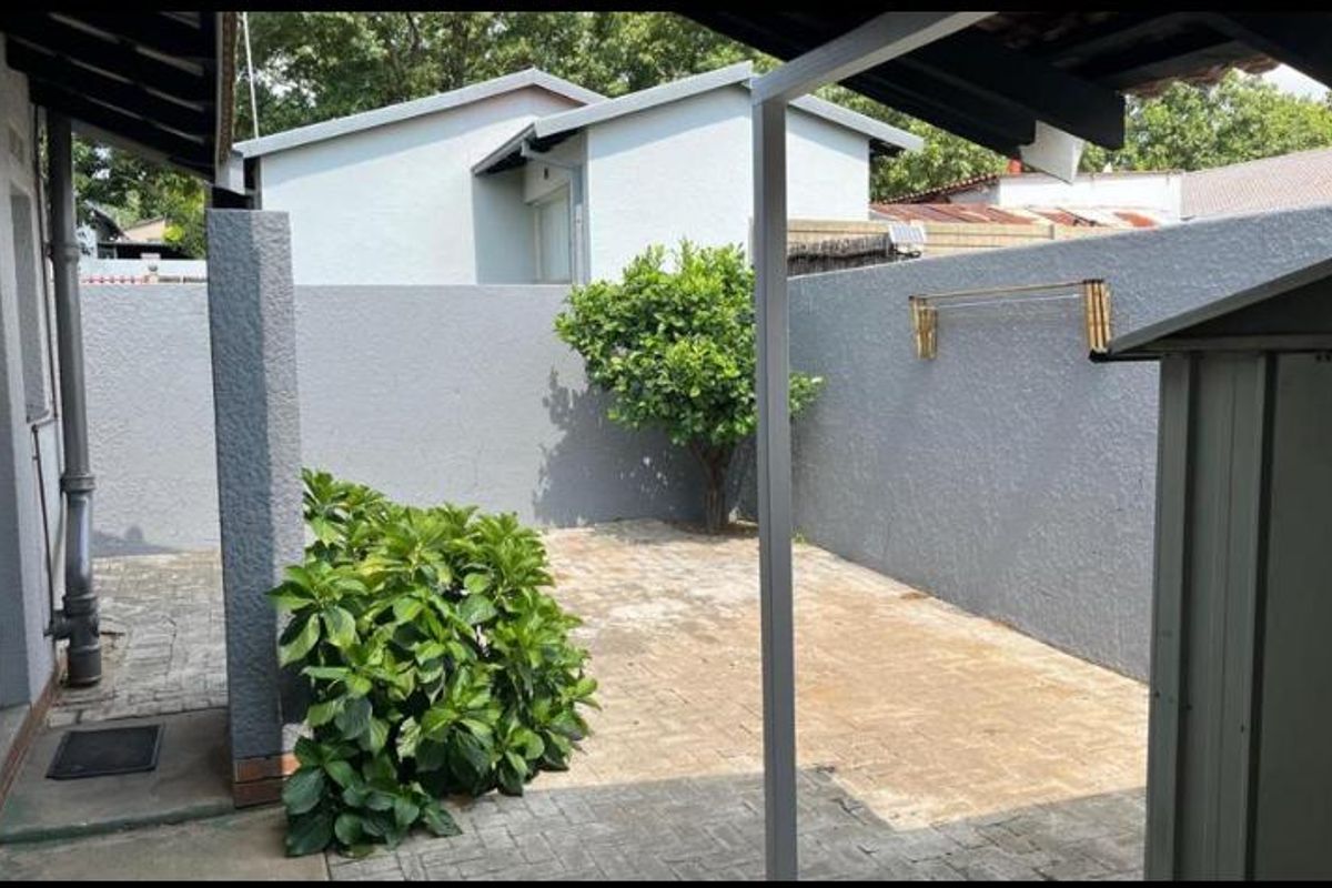 A private rear courtyard featuring paved flooring, a covered patio area, and perimeter boundary walls.