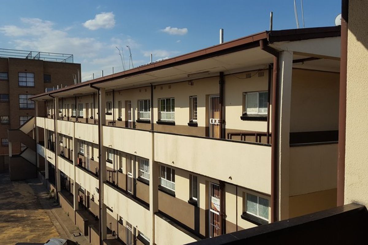 Exterior view of a multi-story apartment block featuring open-air walkways, balconies, and external staircases.