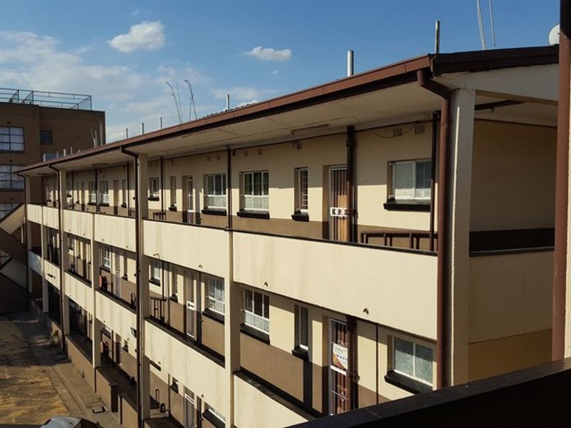 Exterior view of a multi-story apartment block featuring open-air walkways, balconies, and external staircases.
