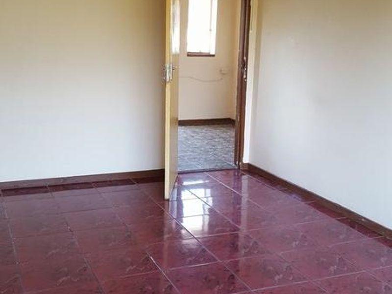 An empty bedroom featuring tiled flooring and a doorway leading to an adjacent room.