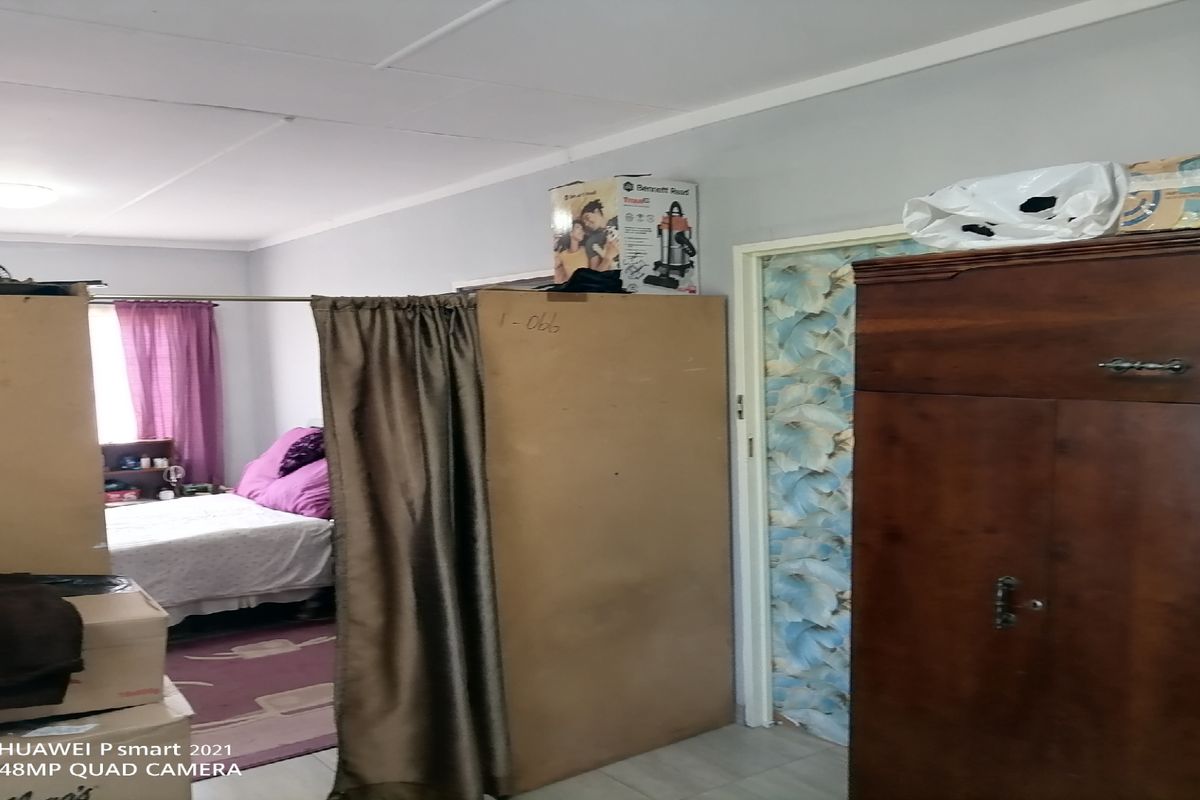 A bedroom space featuring tiled flooring and wallpapered accents, currently partitioned with temporary room dividers.
