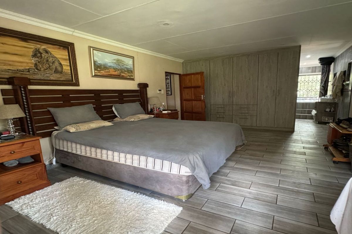 Spacious bedroom featuring built-in wooden cabinetry, tiled flooring, and an en-suite bathroom area.