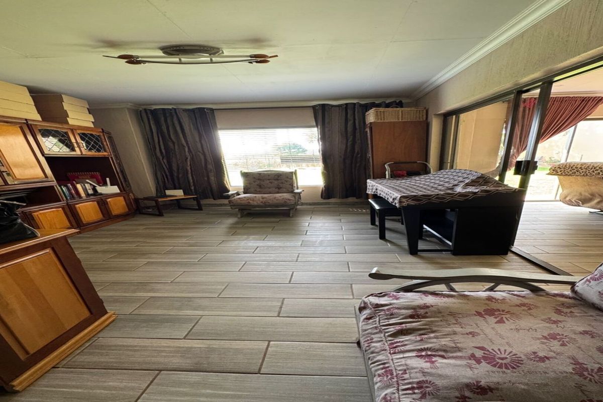 Spacious living area featuring large format floor tiles, built-in wooden cabinetry, and sliding glass doors providing access to the outdoor patio area.
