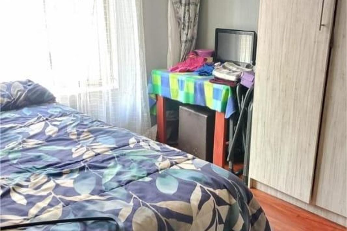 A bedroom featuring wood-look flooring and a built-in wardrobe, offering a functional space with natural light from the window.