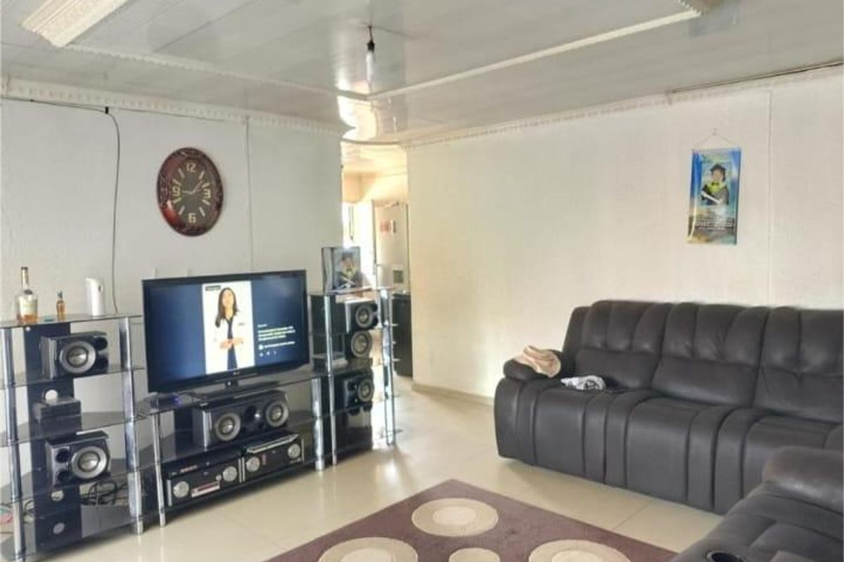 A spacious living room featuring tiled flooring and a textured wall finish, providing a functional and comfortable area for relaxation.