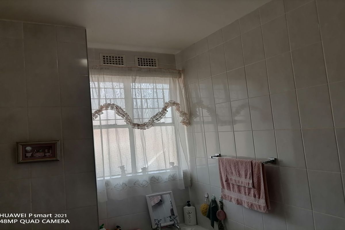 A functional bathroom featuring full-height wall tiling, a window for natural light, and a wall-mounted towel rail.