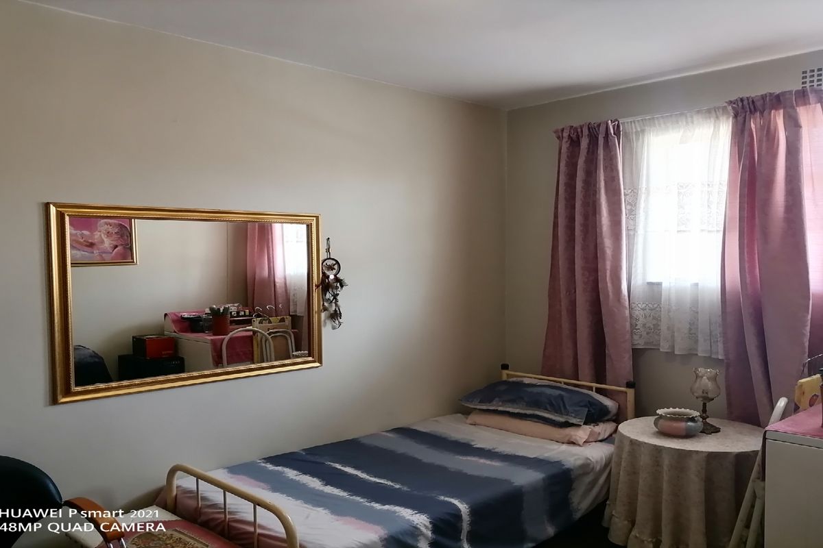 A functional bedroom featuring a window with curtains and neutral wall finishes, providing a comfortable and well-lit living space.