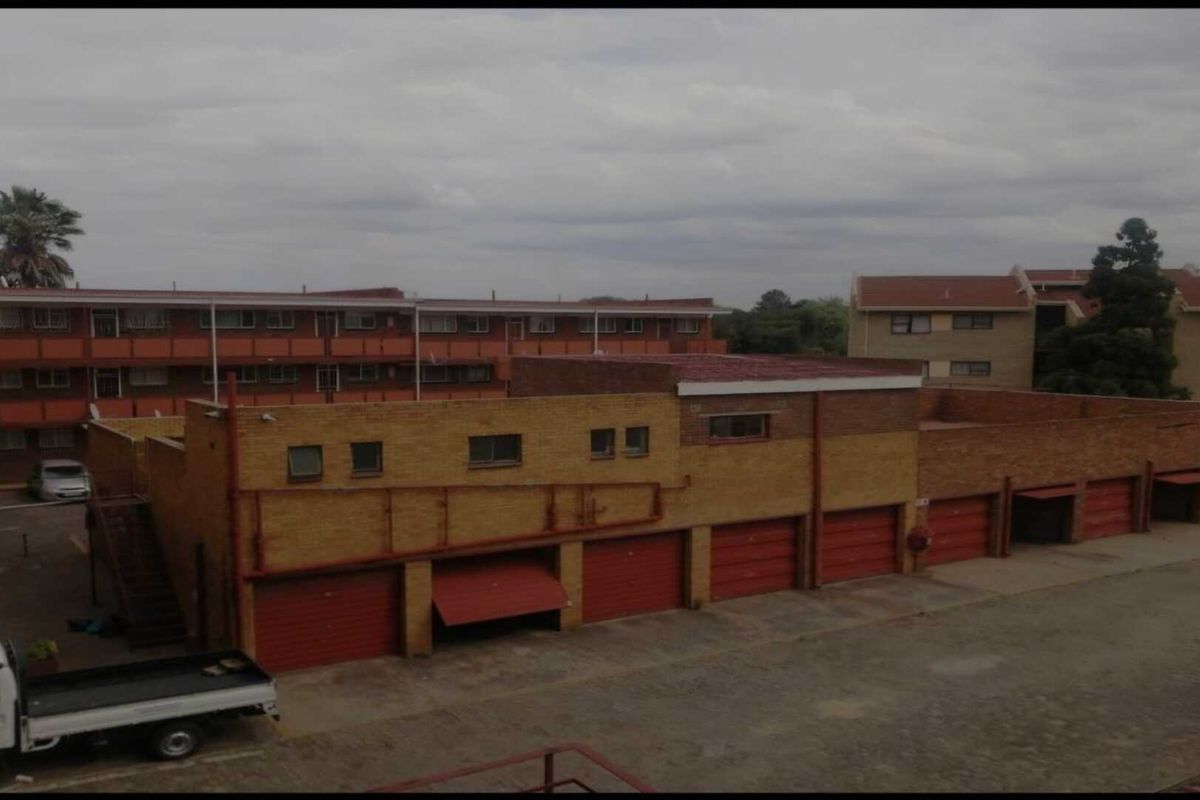 An elevated view of a residential complex featuring a row of brick garages with red roll-up doors and surrounding apartment buildings.