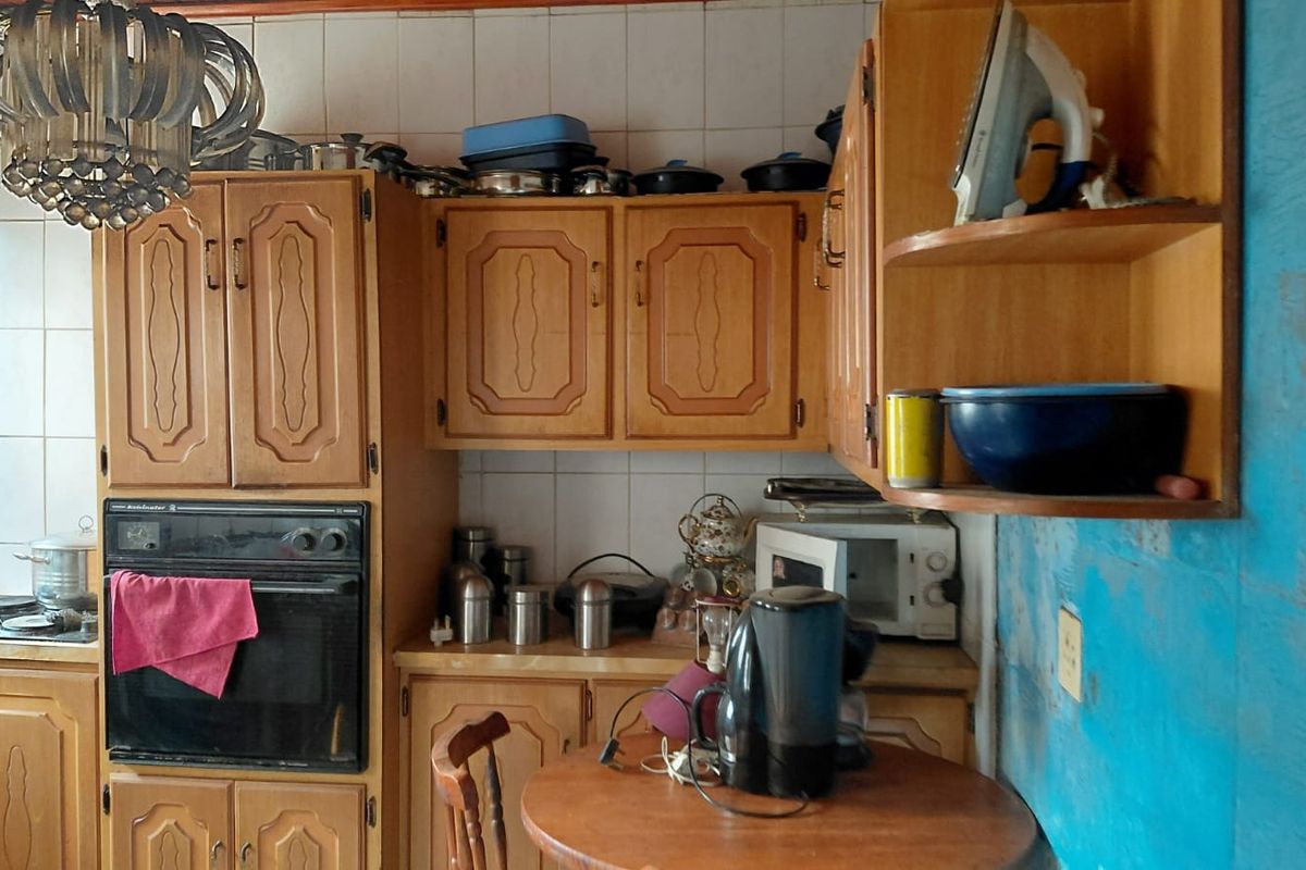 A dated kitchen featuring traditional wooden cabinetry, a built-in oven, and a tiled backsplash, offering a functional layout with potential for modernization.