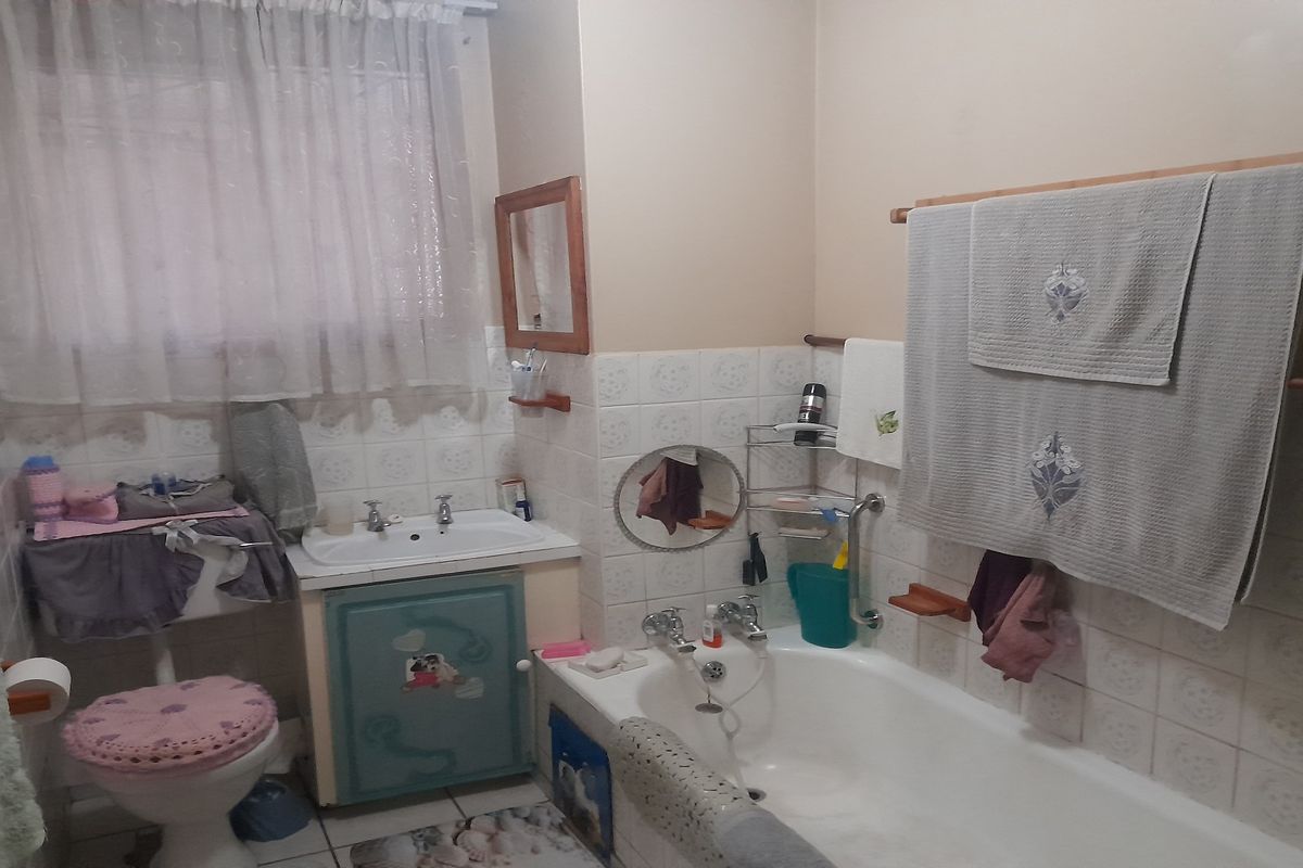 A dated bathroom featuring a standard bathtub, pedestal-style vanity with storage, and wall-mounted tiling.