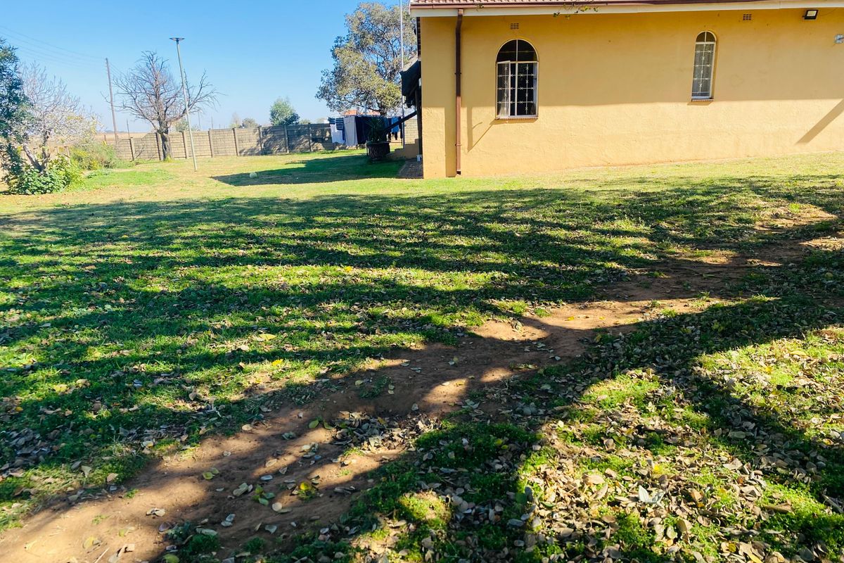 A view of the rear garden and side elevation of the house, featuring arched windows and a tiled roof.