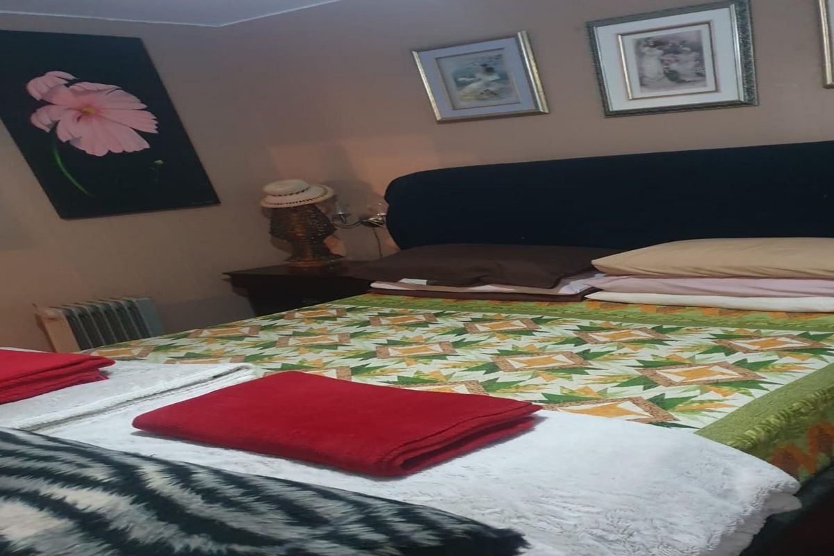 A bedroom featuring a double bed with a patterned quilt and neutral wall tones.