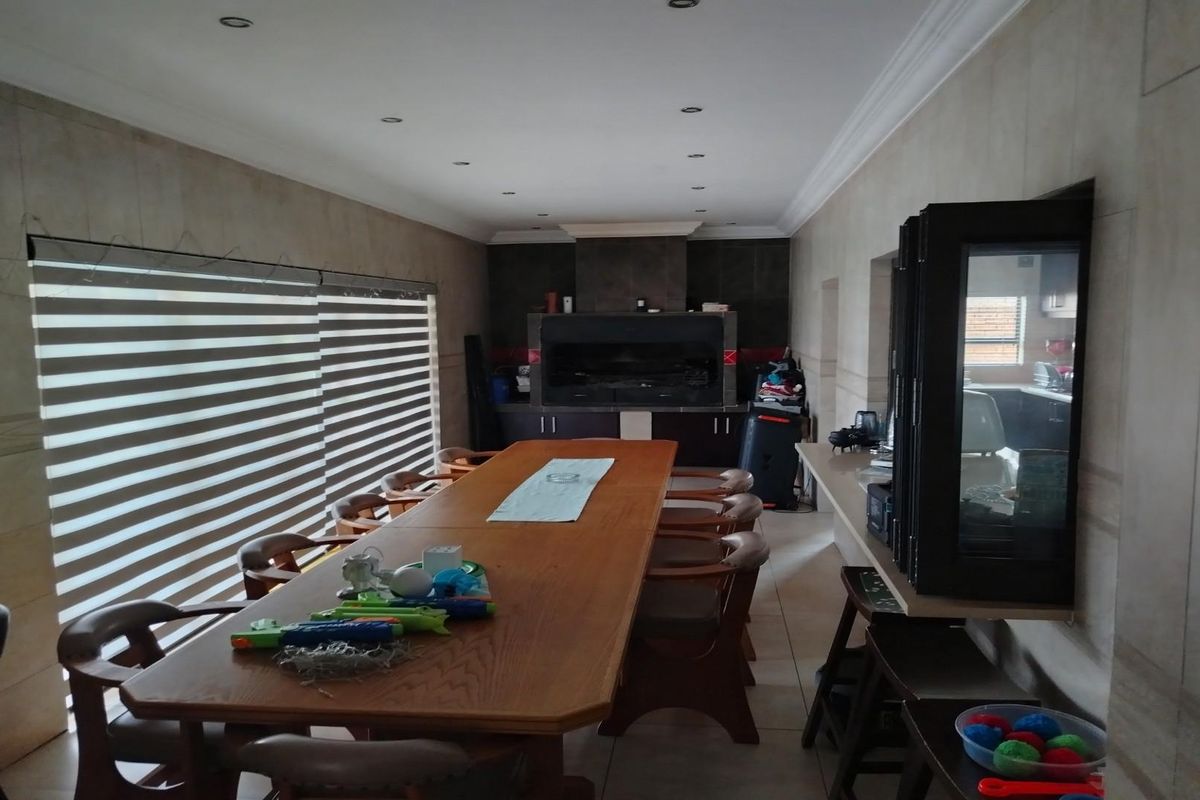 Spacious indoor entertainment area featuring a built-in braai, tiled flooring, and recessed ceiling lighting, ideal for hosting gatherings.