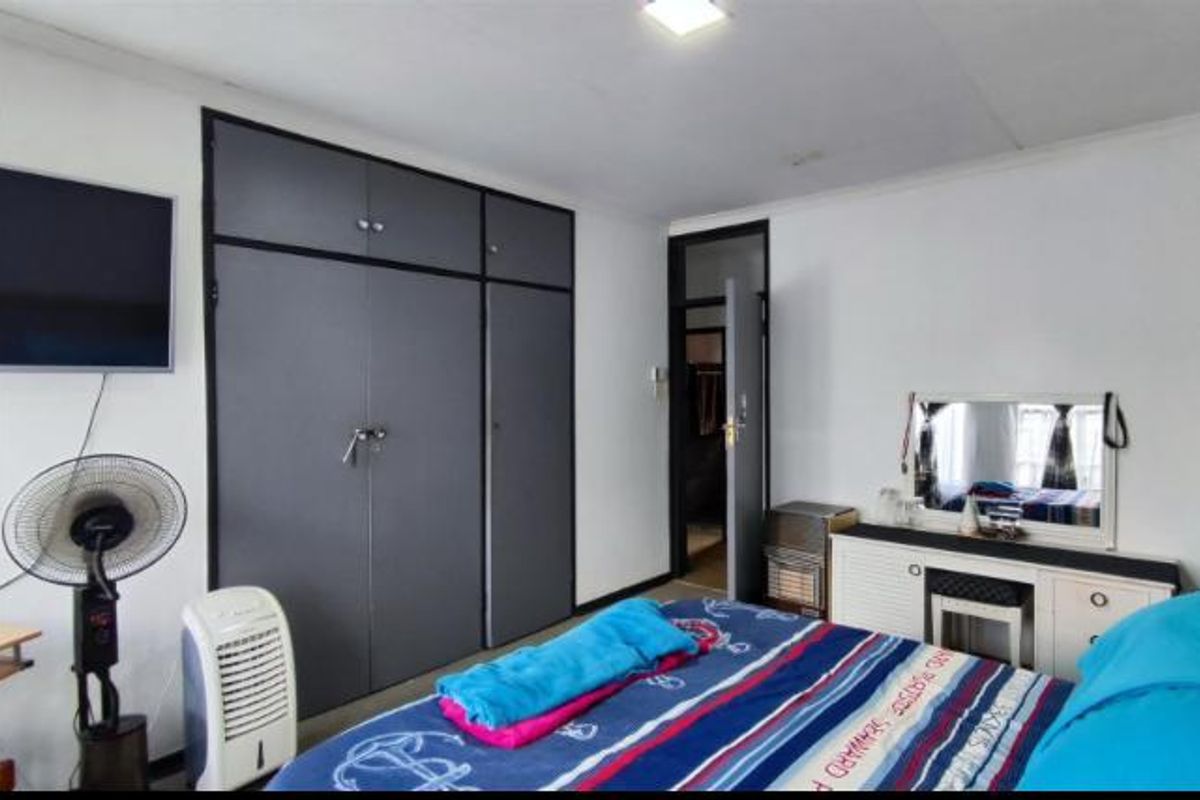 A bedroom featuring built-in cupboards with dark grey doors and a neutral interior finish.