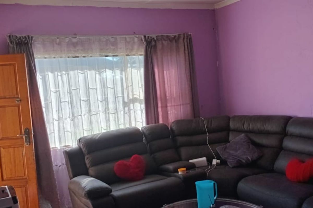 A living room featuring purple painted walls, a wooden door, and a large window with curtains.