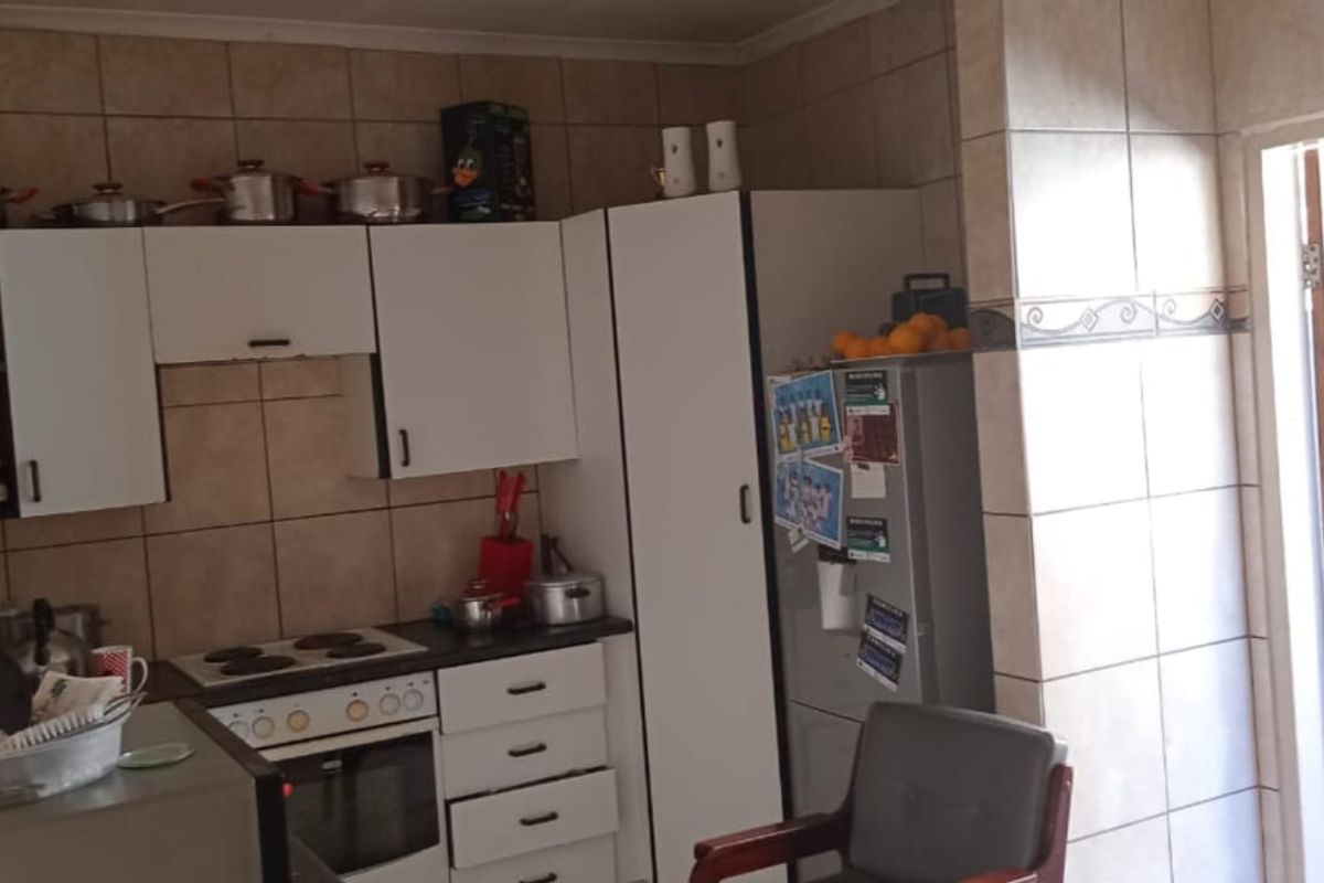 A functional kitchen featuring white cabinetry, built-in oven and hob, and tiled walls, with direct access to an outdoor area.