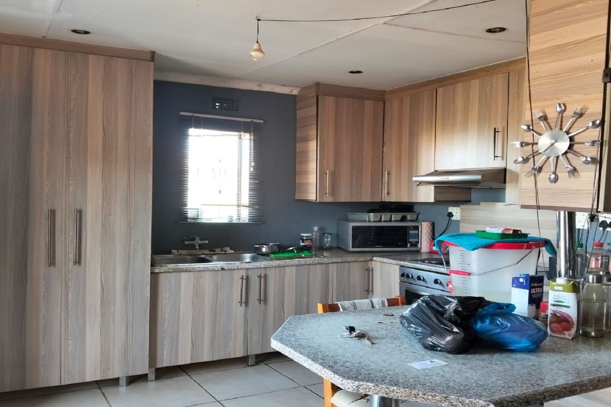 A functional kitchen featuring wood-look cabinetry, granite-style countertops, a built-in oven with extractor fan, and tiled flooring.