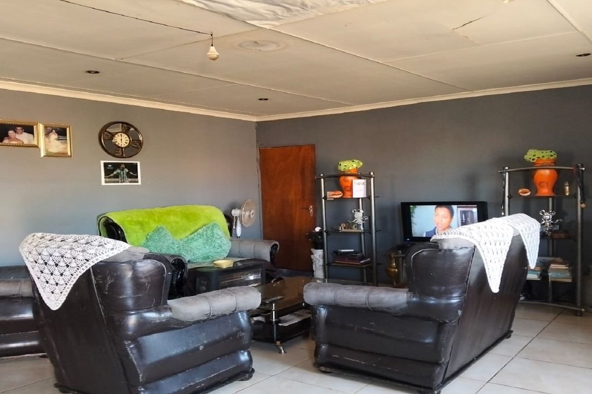 A living room featuring tiled flooring and grey painted walls, with a standard door and ceiling lighting fixtures.