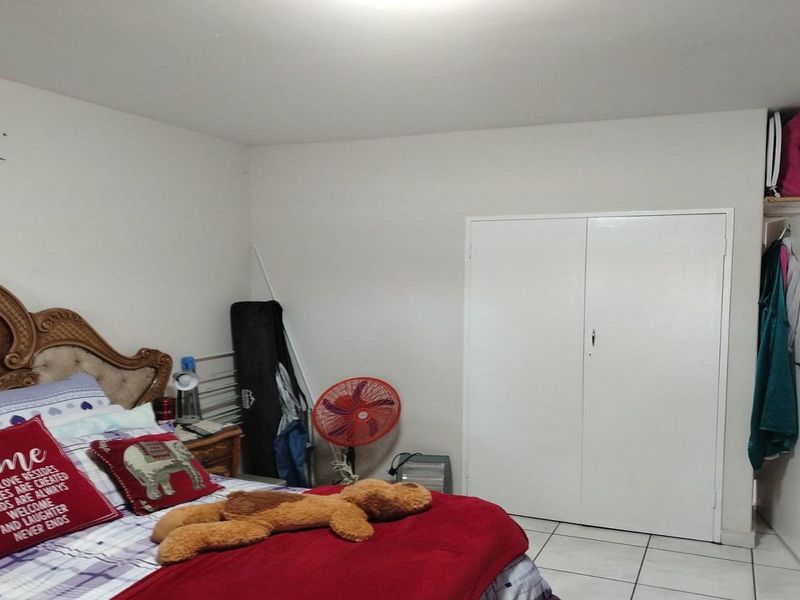 A bedroom featuring tiled flooring and a built-in wardrobe, providing functional storage space within the room.
