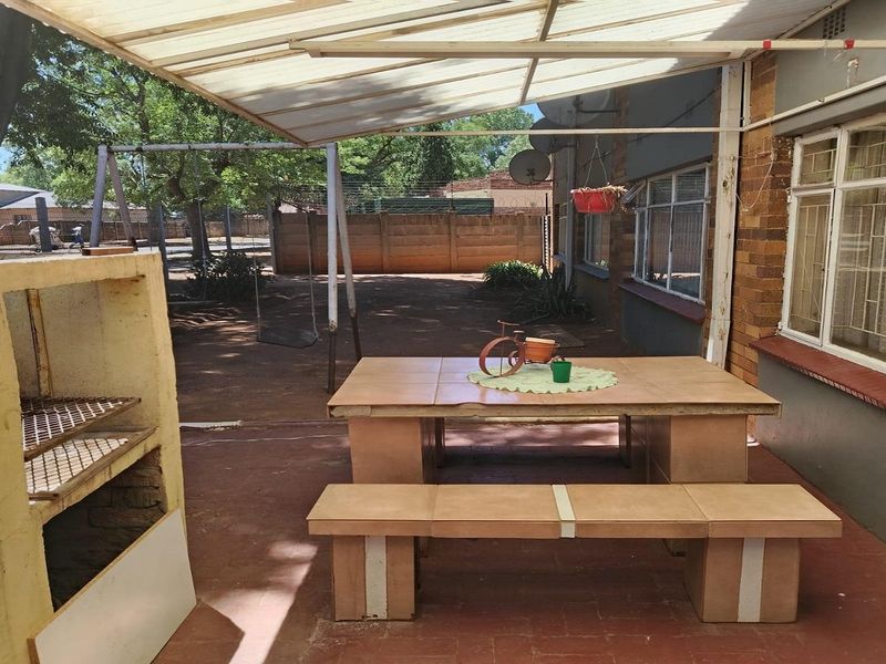 Covered outdoor patio area featuring a built-in braai, tiled flooring, and direct access to the rear garden space.