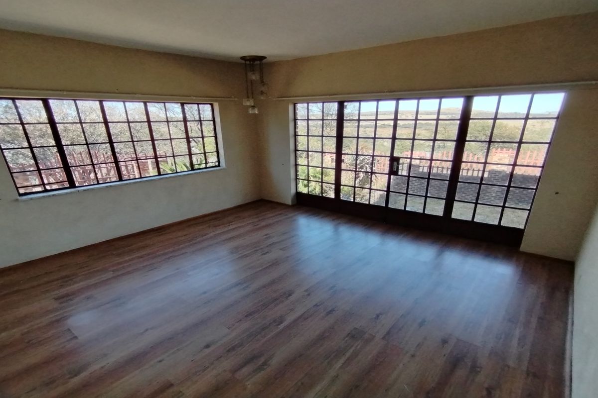 A bright, empty living room featuring wood-look laminate flooring and large windows that provide ample natural light and scenic views.