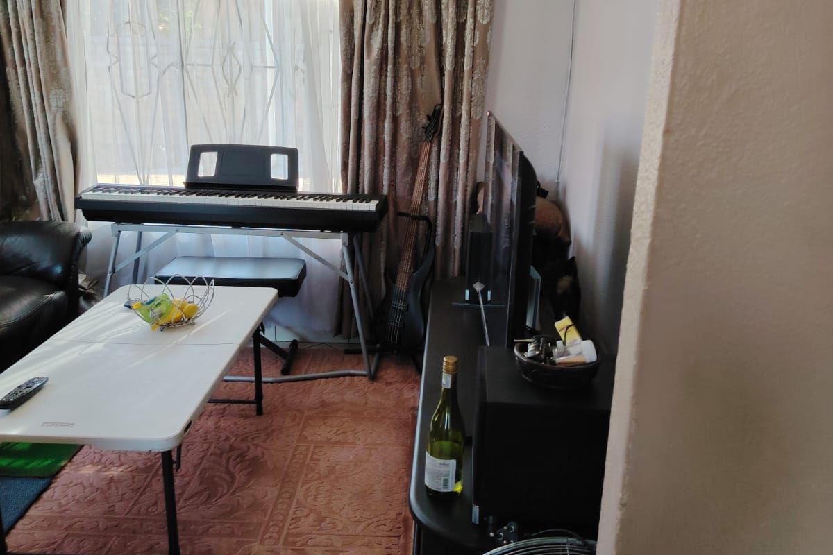 A living room area featuring tiled flooring, large window with curtains, and neutral wall finishes.
