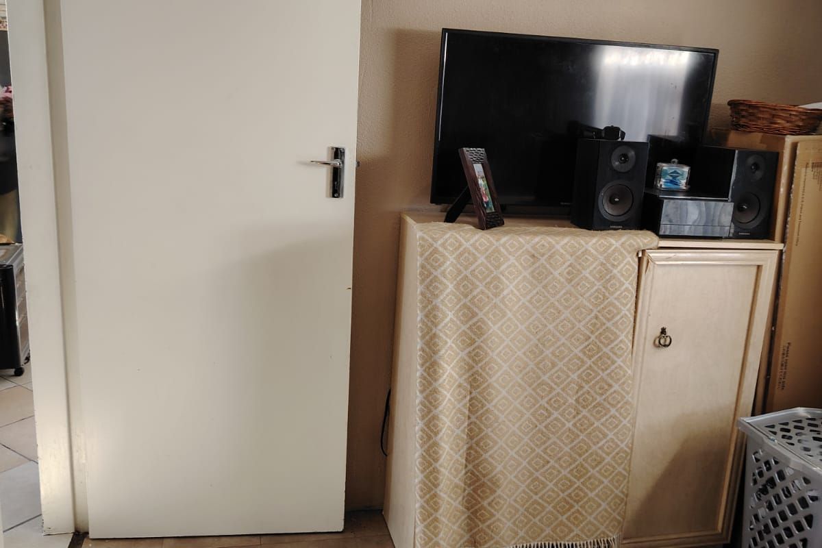 A bedroom interior featuring standard door access and tiled flooring, currently utilized as a living space with storage cabinetry.
