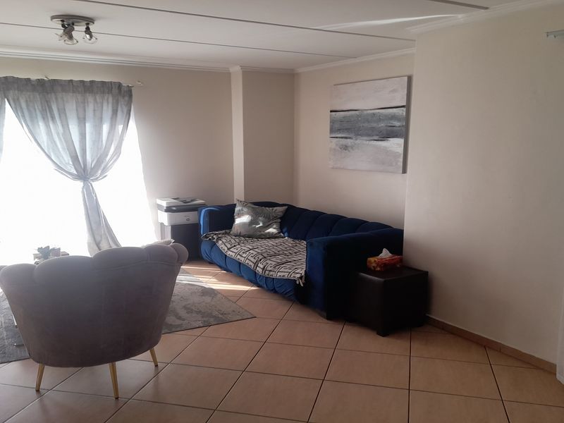 A bright living room featuring tiled flooring and a large sliding glass door providing access to the exterior.
