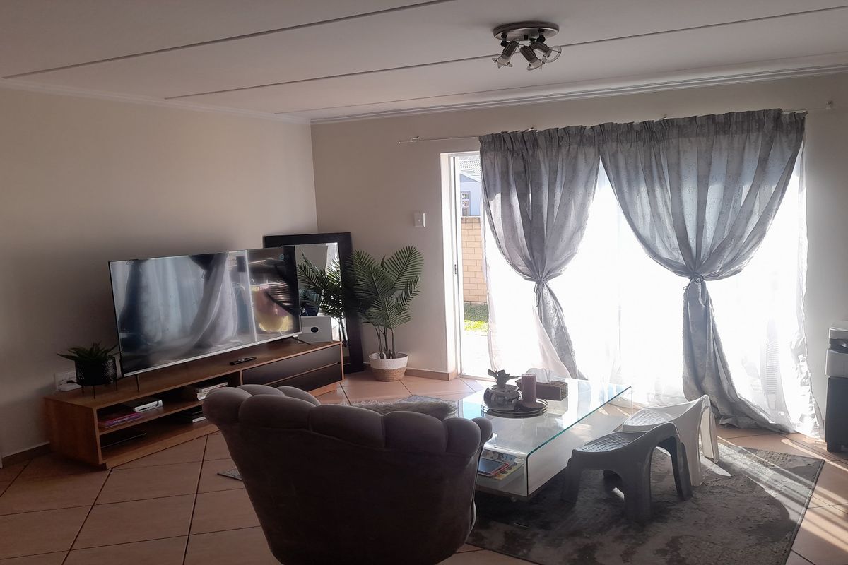 A comfortable living room featuring tiled flooring and a large sliding glass door that provides natural light and access to the outdoor area.