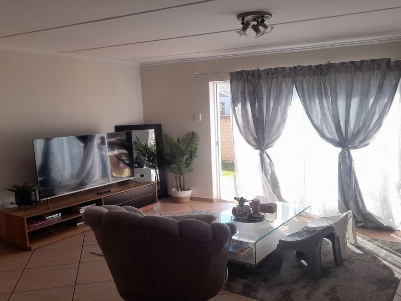 A comfortable living room featuring tiled flooring and a large sliding glass door that provides natural light and access to the outdoor area.