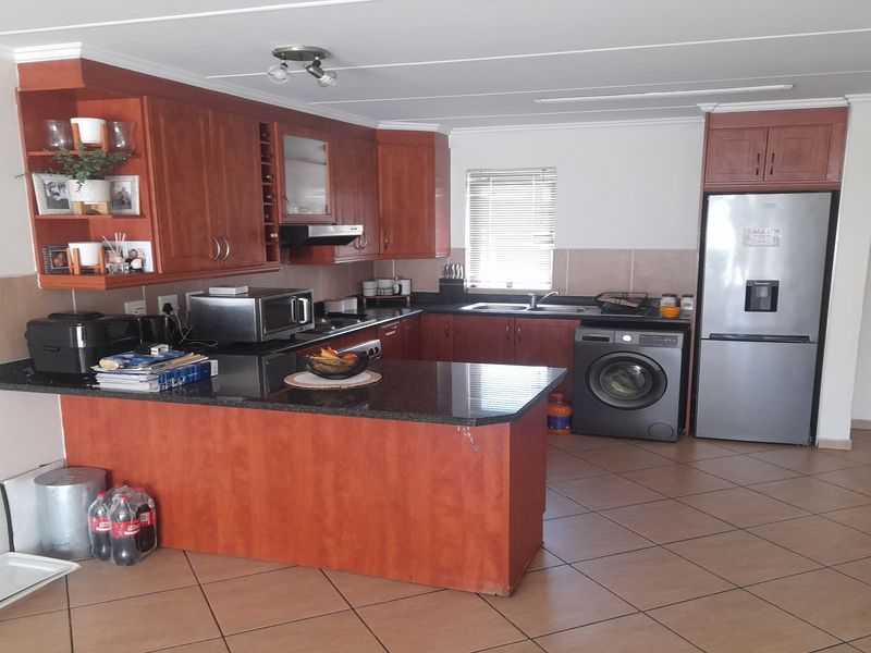 A functional kitchen featuring wooden cabinetry, granite countertops, tiled flooring, and dedicated space for integrated appliances.