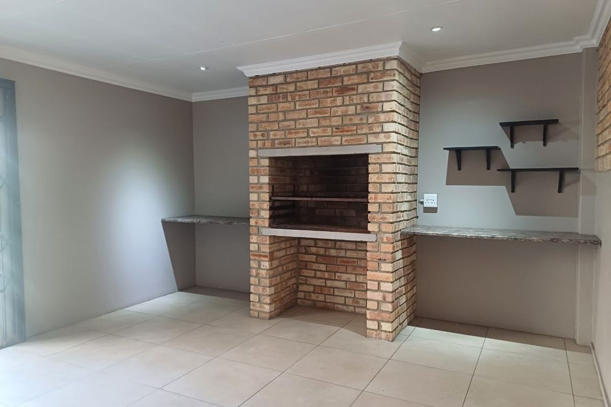 An indoor entertainment area featuring a built-in brick fireplace, tiled flooring, and integrated stone-look countertops.