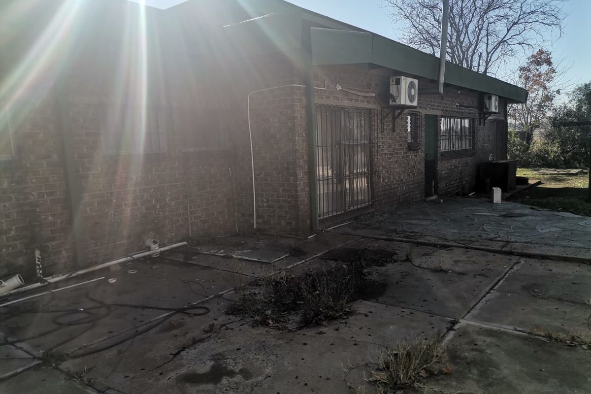 Rear exterior view of the property featuring a brick facade, paved patio area, and mounted air conditioning units.