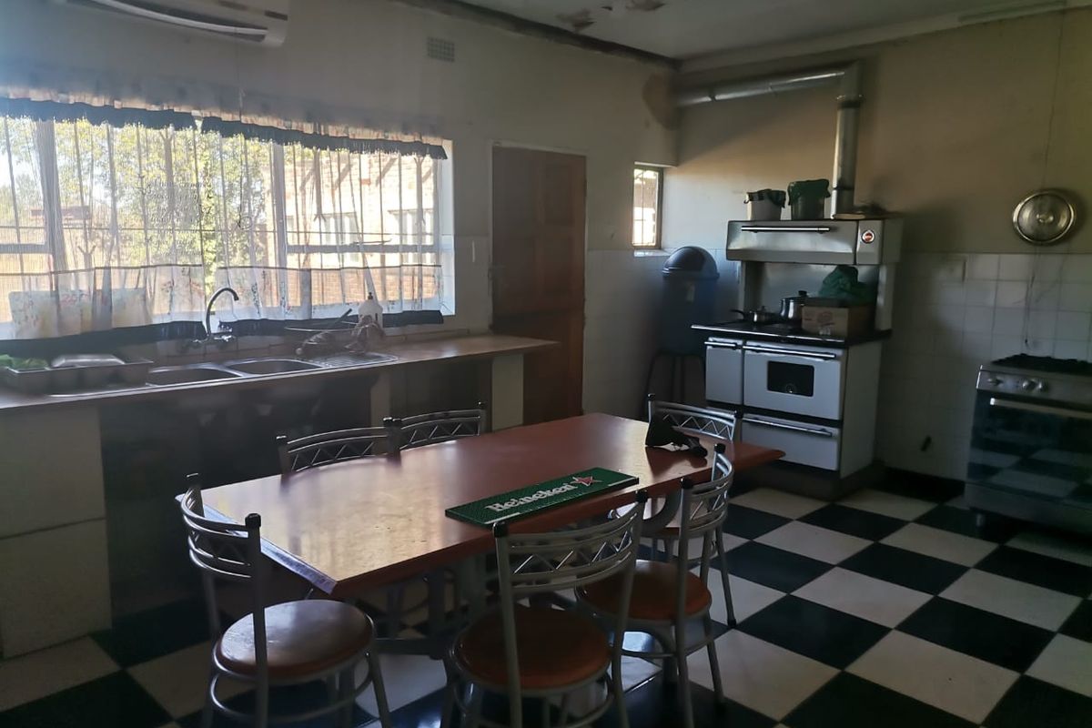 A spacious kitchen featuring a checkerboard floor, built-in cabinetry, a double sink, and a vintage-style stove with an extractor fan.