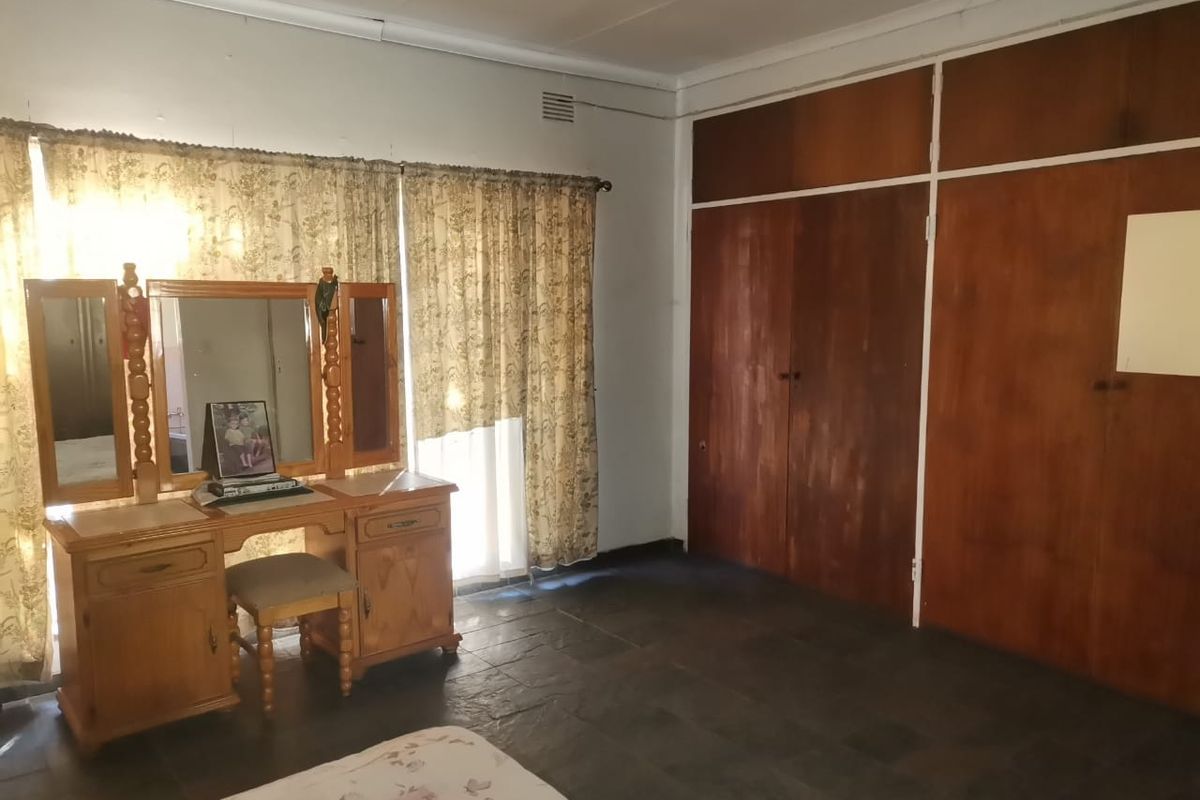 A bedroom featuring built-in wooden cupboards and dark tiled flooring, offering a functional space with classic finishes.