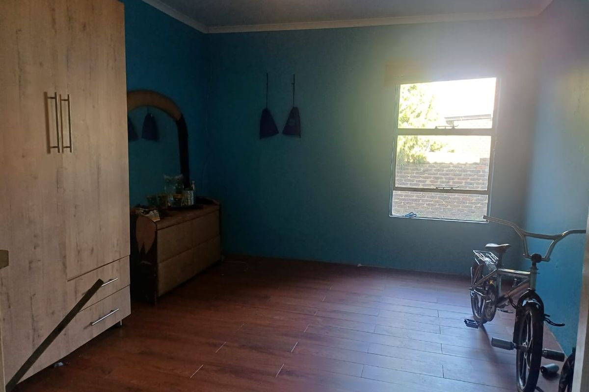 A bedroom featuring wood-look laminate flooring, a built-in wardrobe, and a window providing natural light.
