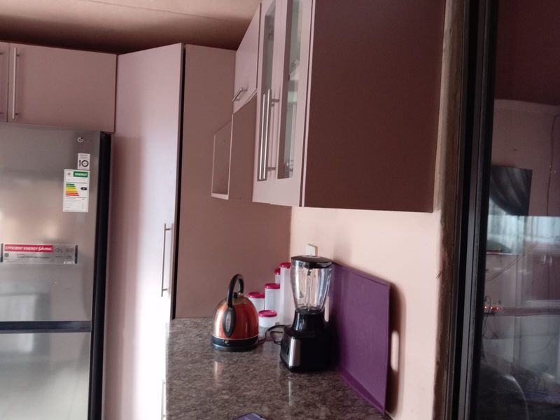 A functional kitchen area featuring built-in cabinetry, stone-look countertops, and a dedicated space for a large refrigerator.