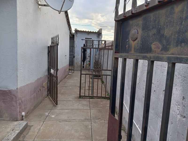 A narrow side passage featuring concrete paving, metal security gates, and exterior wall access.