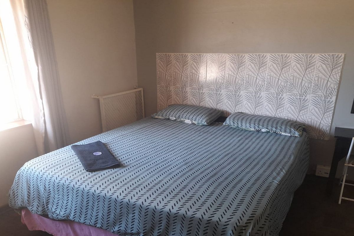 A bedroom featuring a decorative tiled headboard wall and natural light from the side window.