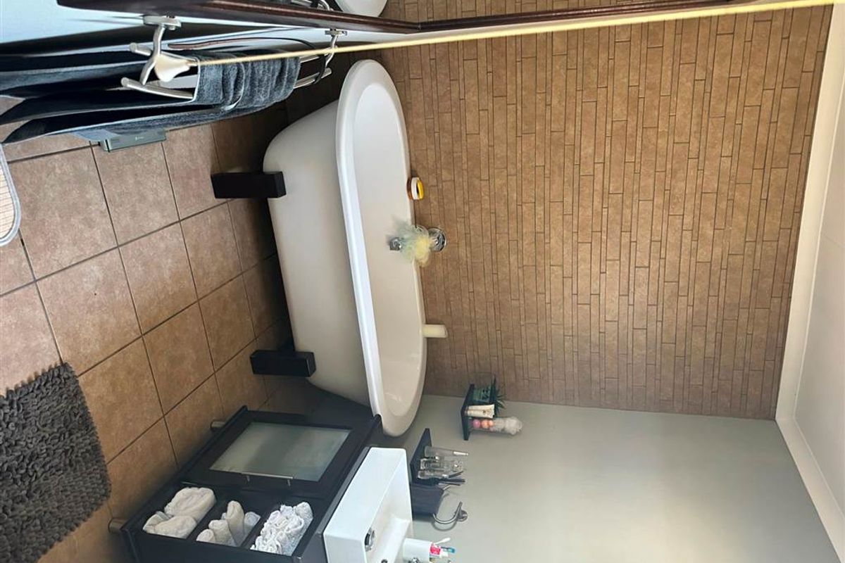A functional bathroom featuring a freestanding bathtub, a modern vanity with a basin, and textured feature wall tiling.