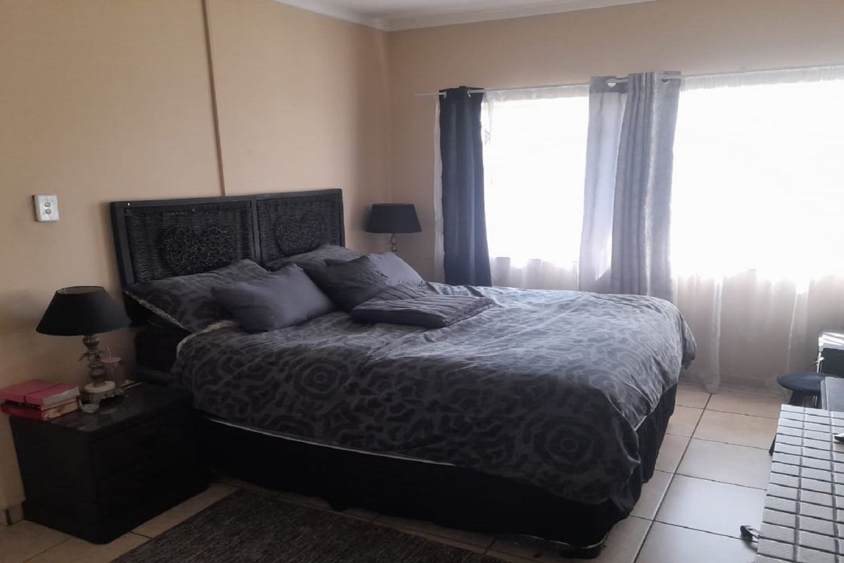 A bedroom featuring tiled flooring and large windows that provide natural light.