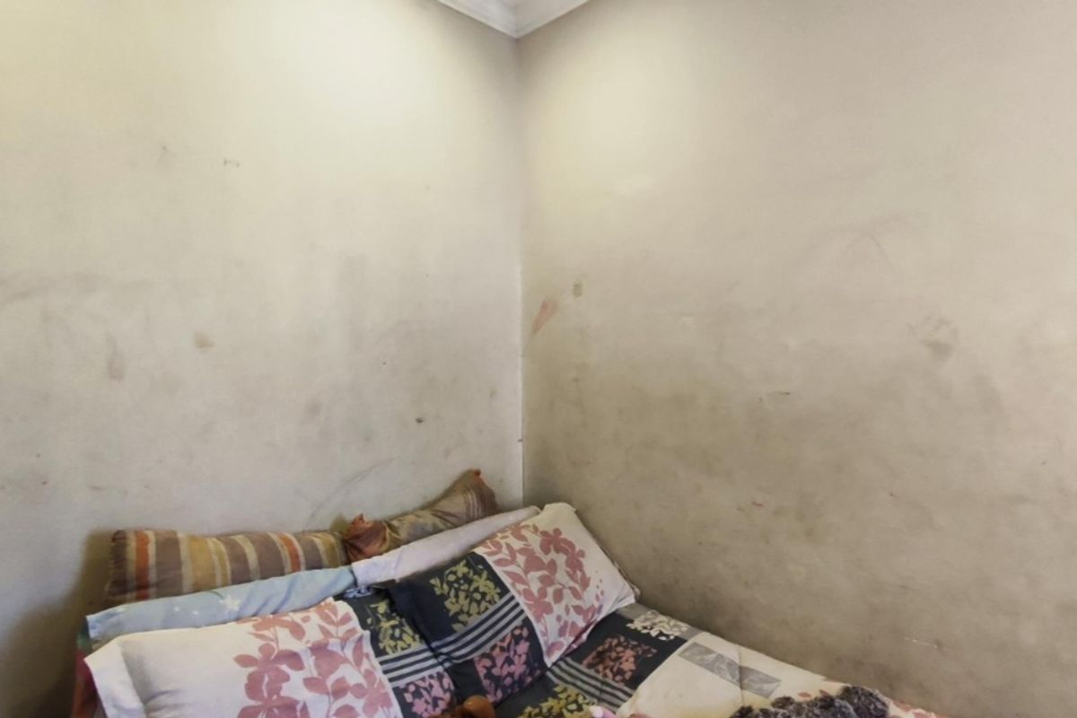 A bedroom corner featuring plain walls in need of maintenance and repainting to restore the space.